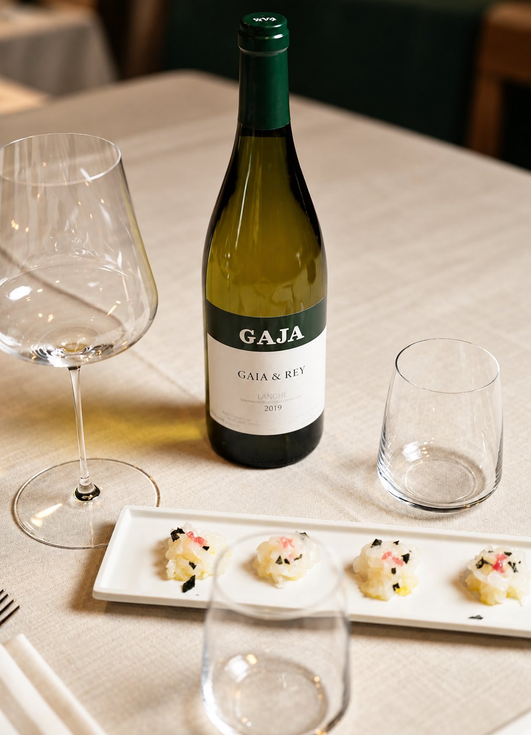 Bottiglia di Gaja & Rey con crudi su piatto bianco