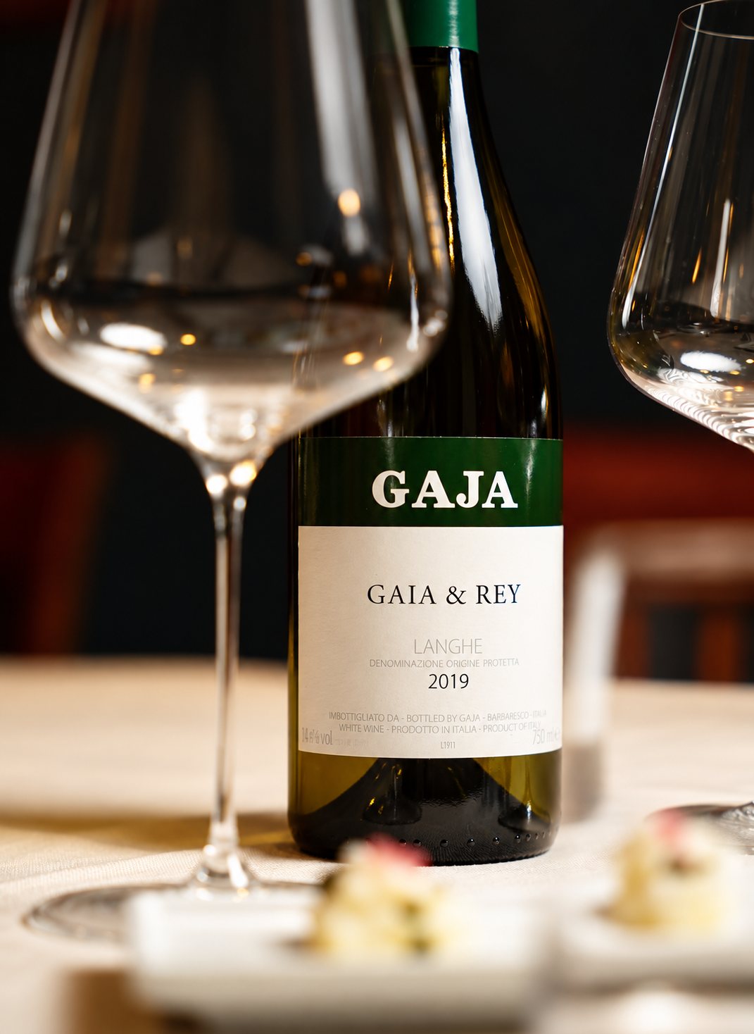 Bottiglia di Gaja & Rey e calici su tavolo apparecchiato